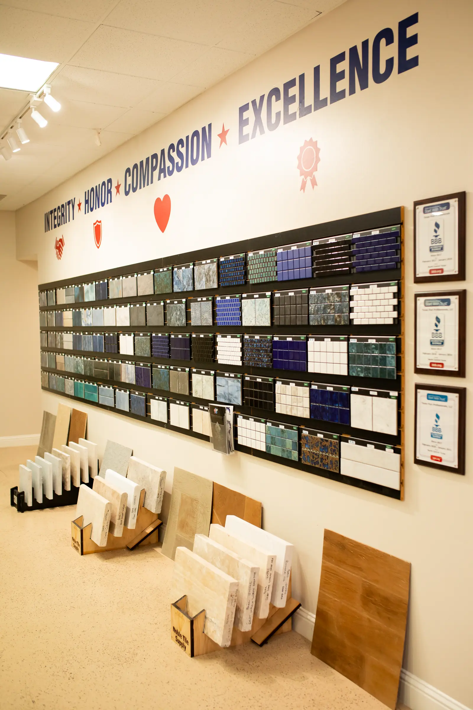 Showroom wall with pool tile samples and the words integrity, honor, compassion, excellence